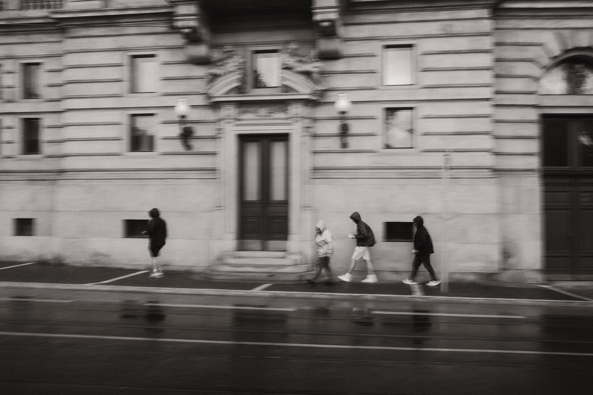 Pohybom rozmazaná čiernobiela fotografia ulice po daždi.