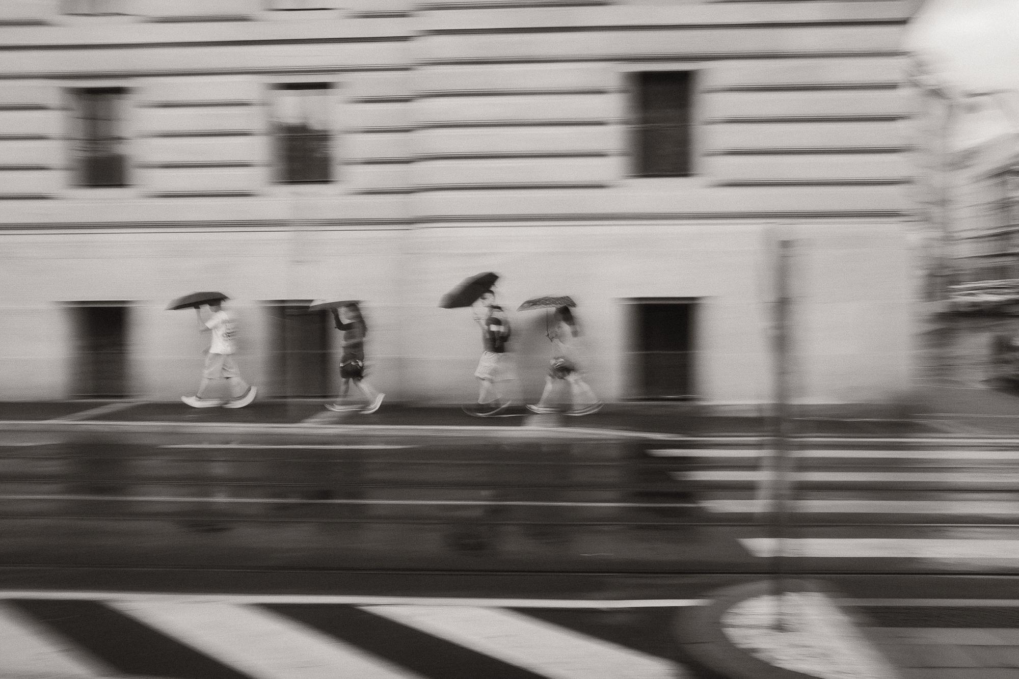 Pohybom rozmazaná čiernobiela fotografia ulice po daždi.