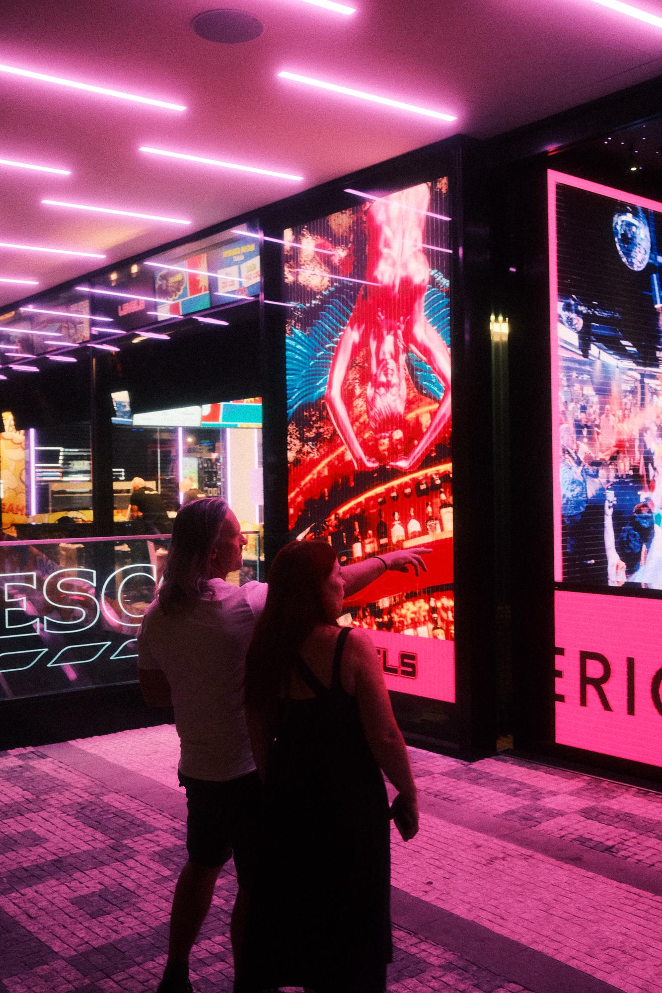 Neónovo osvetlená ulica pred nákupným centrom v Prahe.