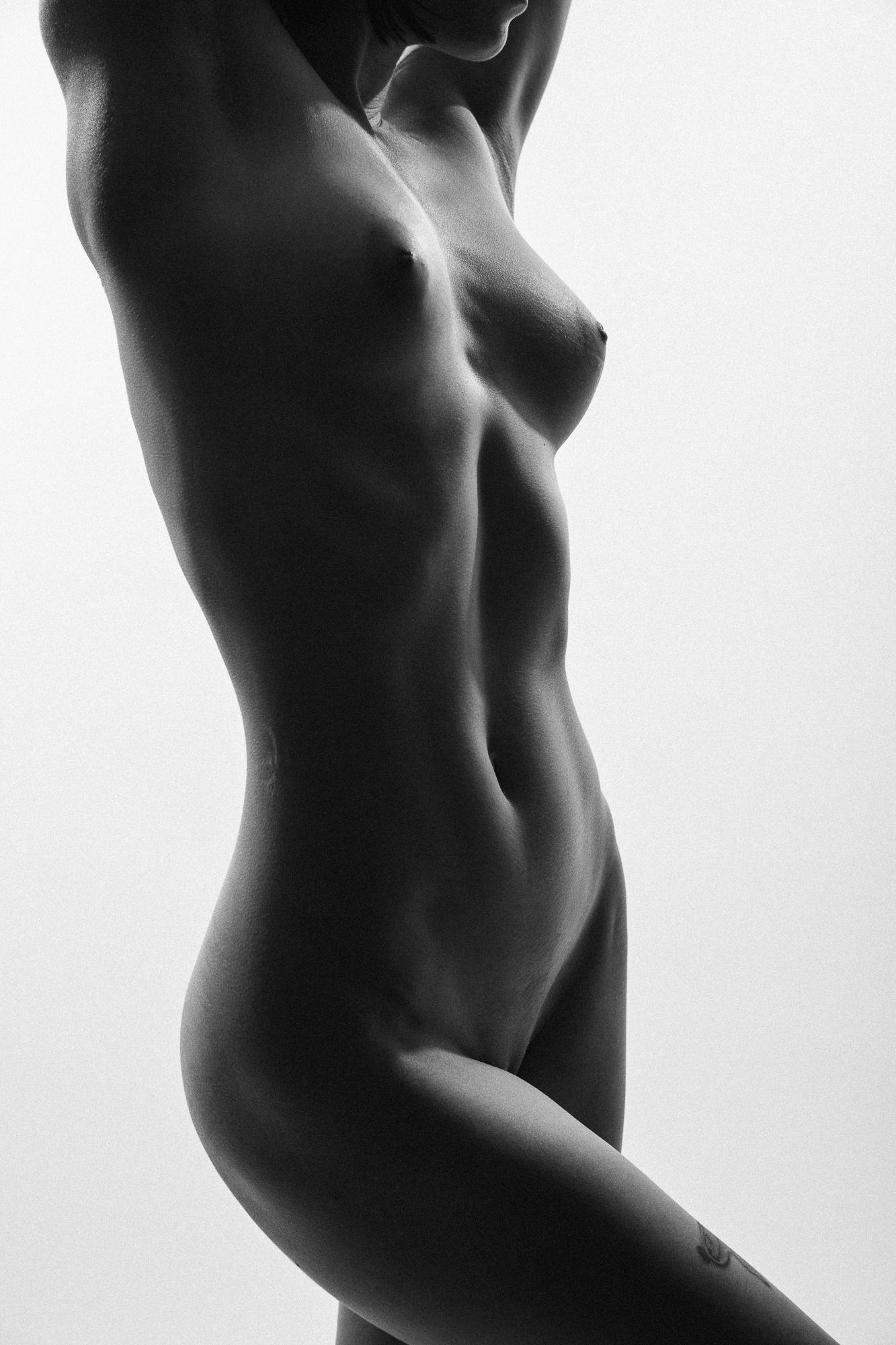 Black and white artistic nude photograph of a woman showcasing graceful body lines and delicate skin textures. Studio Pezinok.