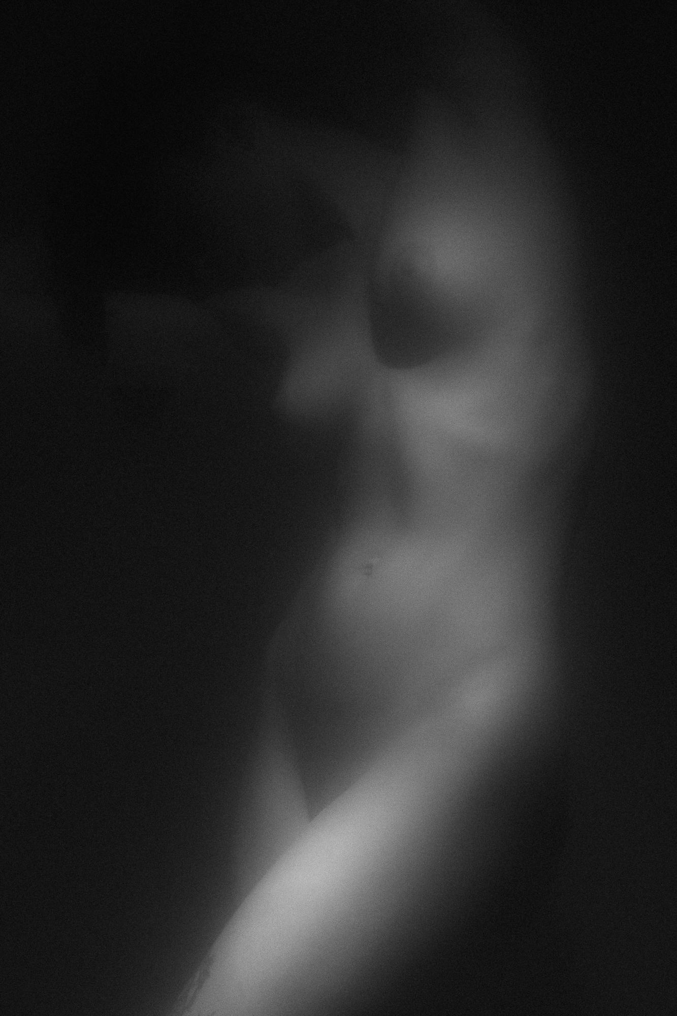 Black and white artistic nude photograph capturing the delicate curves of a woman's body in light and shadows, emphasizing gentle composition and aesthetics, Studio Pezinok.