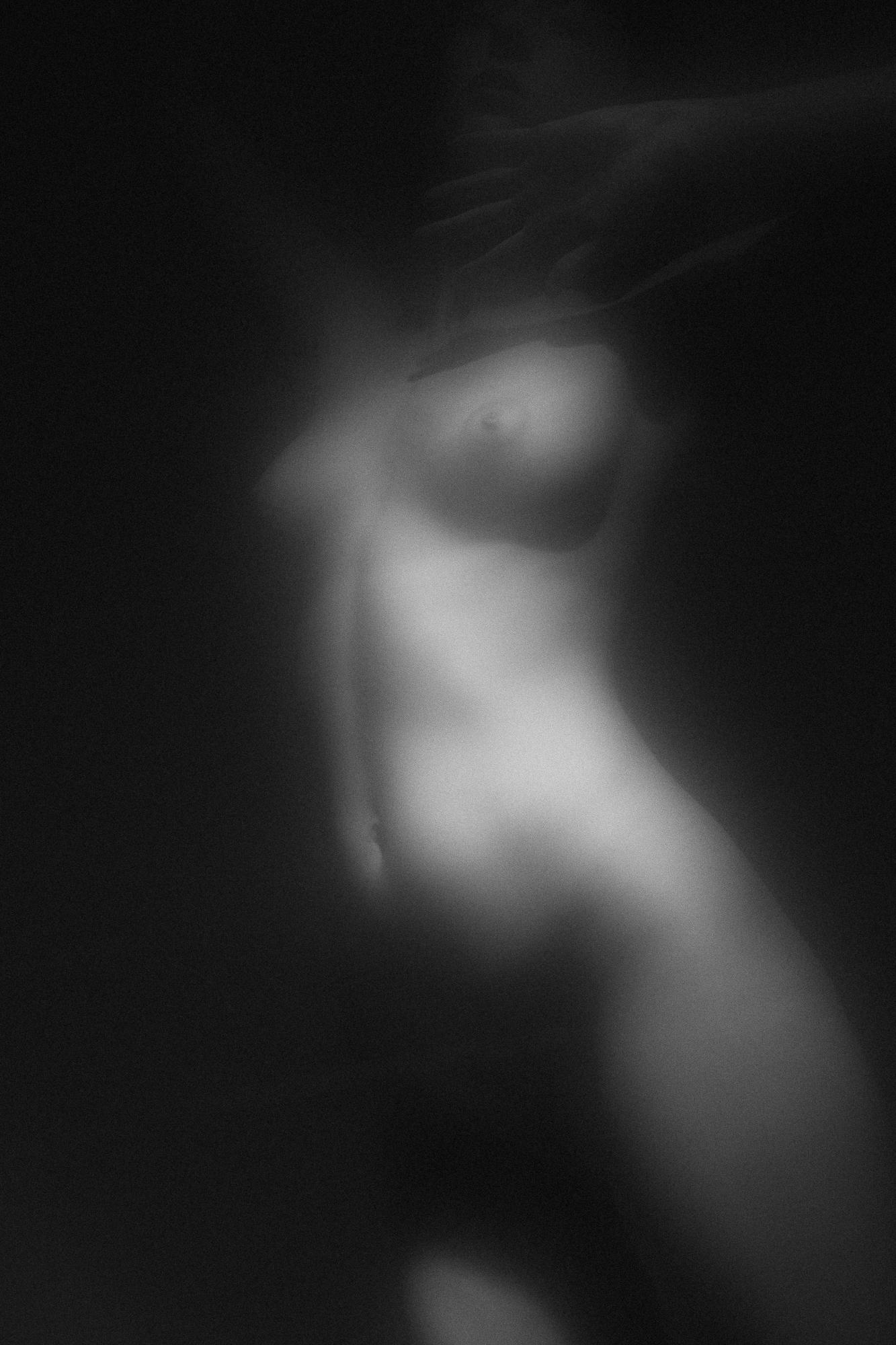 Black and white artistic nude photograph capturing a soft silhouette of a woman's body in delicate light, creating an ethereal beauty. Studio Pezinok.