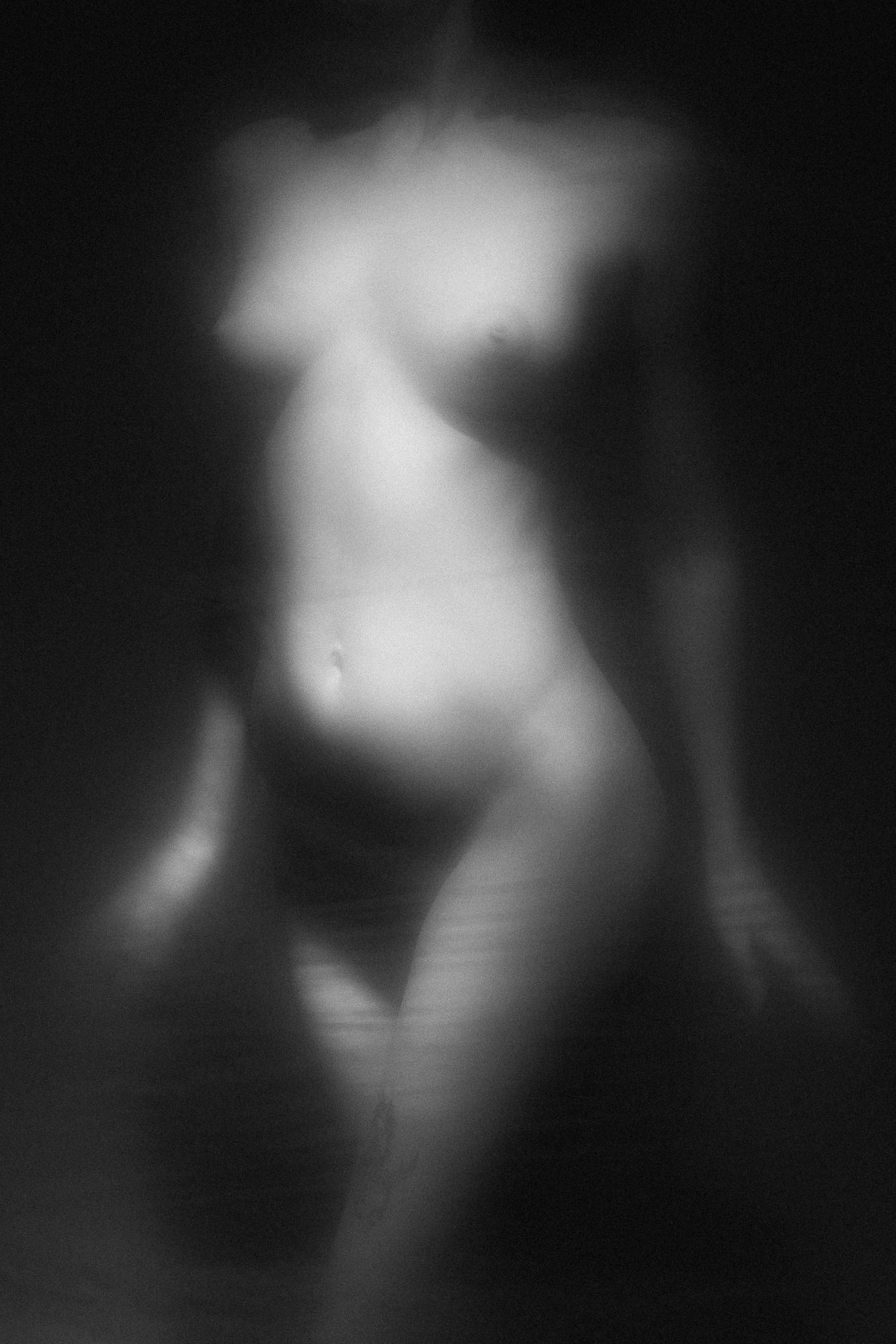 Black and white artistic nude photograph capturing the delicate curves of a female body with a gentle play of light and shadows. Studio Pezinok.